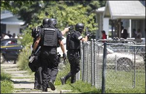 Members of the Toledo Police Department SWAT unit move into a home after a shooting on Bricker near Doyle today.