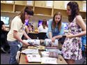 Co-editors Megan Russ, left, Samantha Sieren and Kelly Kilpatrick sort through extra issues of "The Somethin" for keepsakes during their Newspaper class.