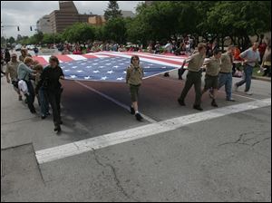 Marchers carry a large American flag down Jackson Street during the Memorial Day Parade in downtown Toledo last year.
