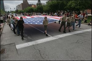 Marchers carry a large American flag down Jackson Street during the Memorial Day Parade in downtown Toledo last year.