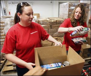 Katie Shephard, left, and Lindsay Antonio fill boxes at the Toledo Seagate Food Bank as part of the KeyBank 'Neighbors Make The Difference Day.'