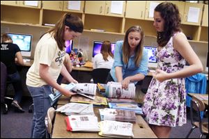 Co-editors Megan Russ, left, Samantha Sieren, and Kelly Kilpatrick sort through extra issues of the student-run newspaper, The Somethin'. It was first published at Perrysburg High School in 1922.