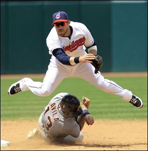 Cleveland Indians' Jason Kipnis jumps over Detroit Tigers' Alex Avila as Kipnis looks toward first base in the sixth inning.