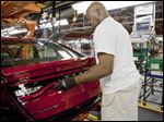  An assembly line worker attaches the taillights on a 2013 Dodge Dart at Chrysler’s Belvidere assembly plant in Belvidere, Ill. The five-seat sedan is key to the automaker’s future, its CEO says.
