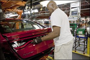 An assembly line worker attaches the taillights on a 2013 Dodge Dart at Chrysler’s Belvidere assembly plant in Belvidere, Ill. The five-seat sedan is key to the automaker’s future, its CEO says.