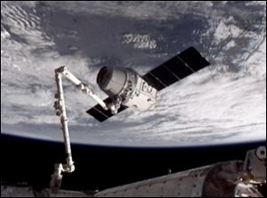 The SpaceX Dragon commercial cargo craft, top, after Dragon was grappled by the Canadarm2 robotic arm and connected to the International Space Station.