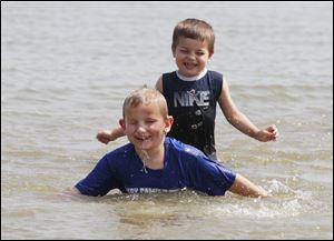 Sean Leese, 5, front, and his brother Sam Leese, 4, enjoy the weather at the Luna Pier beach, Friday. The pair were cooling off with their father Mike Leese, Waterville.