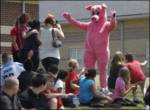 Principal Jack Renz dons a pig costume then kisses a pig,
in front of his students at East Broadway Elementary, who exceeded by more than 10,000 pages the reading goal he had set for them. Lester Marks of Monroe, who owns Ned the pig, held him for the kiss Friday.