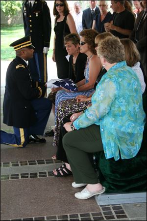 The Rev. John Baptist Gabriel, an Army captain, presents the ceremonial flag to the family.