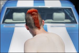 Bob Maier, 27, sports a red Mohawk in front of his blue and white 1966 Chevy Caprice on Friday at Danny B's Body Shop, 1136 E. Broadway, in East Toledo.