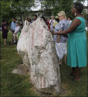 Cece Norwood touches the Violence Against Women Memorial Rock during vigil for Jazmon Denise Hoskins at the Sanger Branch library.