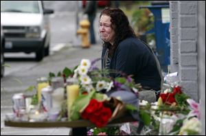 Stacy Davis cries as she sits near a growing memorial at the scene of where a gunman killed four people and severely wounded another in a cafe a day earlier, Thursday, in Seattle.