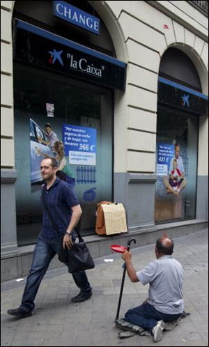 A man begs for money outside a bank in Madrid on Sunday. Spain's grinding financial misery will get worse this year despite the country's request for a European financial lifeline of up to $125 billion to save its banks, Prime Minister Mariano Rajoy said.