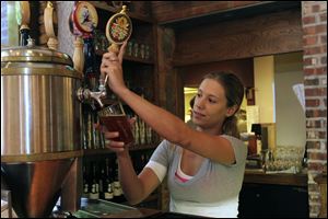 Alicia Weiss draws a pint of the Old Siege Lifter Honey Brown at the Maumee Bay Brewing Co. The ale, which uses locally sourced honey, has an alcohol by volume content of 5.2 percent