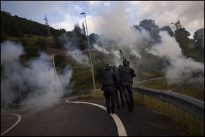 Officers patrol amid smoke from rockets launched by miners protesting Spain's austerity measures.