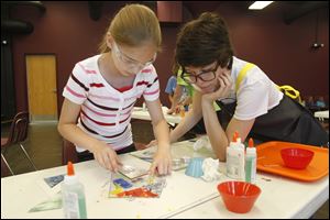 Emma Lazor, left, gets help making her creation from instructor Emily Repp at the Toledo School for the Arts as part of the Glass Art Conference. The Glass Art Society opens its annual conference today, with most activities centered in SeaGate  Convention Centre and the Toledo Museum of Art. Page D1 in today’s Peach
Section features artist Fred Wilson, who is to give a free talk Friday at 7 p.m. in the
museum’s Peristyle Theater. To read The Blade’s coverage of the conference, its
public events, and Toledo’s glass history, go to toledoblade.com/glassarts.