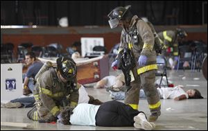 Members of the Toledo Fire Department conduct triage on victims of a mock IED explosion as they train at the Erie Street Market.