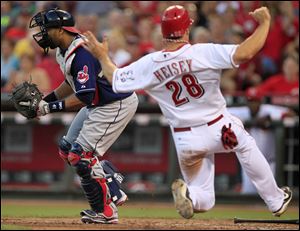 Cincinnati Reds' Chris Heisey (28) scores on a sacrifice fly by Jay Bruce while Cleveland Indians catcher Carlos Santana, left, waits for the throw in the fifth inning in Cincinnati. 