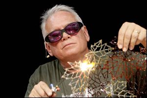 Artist Robert Mickelson works on pieces of leaves made of glass which will be part of a glass sculpture shaped as a bowl during a demonstration during the GAS convention.