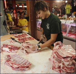 Mariam Maksutova cuts lamb breasts into spare ribs at Sparrow Meat Market in Ann Arbor, Mich.