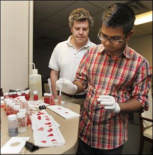 Alex Mejiritski, president of Spectra Group Limited, watches chemist Puran De test synthetic blood the company is making. One firm will be selected to provide the artificial blood. 