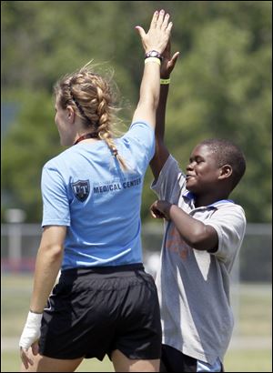 Mykul Hoskins, 10, and team leader Meghan Brown high-five during a soccer game. The local program began June 11 with 125 youths ages 10 to 16. In recent years NYSP at the University of Toledo has been recognized for its programs, lunches, and overall organization by various groups.