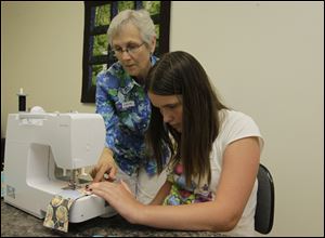 Louise Kimpel, of Perrysburg, helps first-time sewing machine user Allie Bugaj, 11, of west Toledo as she sews her squares together.