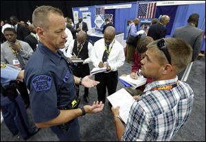 Michigan State Police Trooper Matt McCaul, left, talks with military veteran Christopher Honold, of Canton, Mich.,  in Detroit. Thousands of veterans are in Detroit this week for job fair, open house, small business conference.