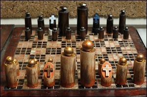 Dowel rod finished chess pieces sit on a back splash glass tiled board.