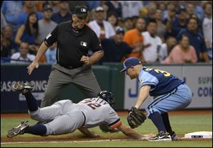 Detroit Tigers' Don Kelly (32) dives back safely to third base as Tampa Bay Rays third baseman Brooks Conrad is late with the tag during a rundown, as umpire Bob Davidson prepares to make the call during the ninth inning of a baseball game in St Petersburg, Fla., Saturday.