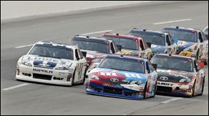 Kyle Busch, front right, takes the lead from Jimmie Johnson, who was on the pole for Saturday night's Quaker State 400 at Kentucky Speedway. The race started with the temperature in the high 90s.