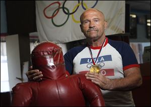 Greg Wojciechowski, during a trip to the Dick Torio Health Club, wears the medal awarded to 1980 Olympians by President Jimmy Carter.