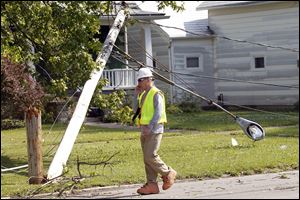 A member of the Ohio Edison hazard response team assess the scene of a downed power line on East 4th St and Washington after Sunday's storm in Port Clinton. 