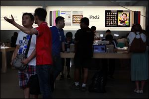 Visitors look at computer products near advertisement for Apple's iPad tablet computer at an Apple store in Beijing, China.