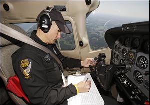 Ohio Trooper Bryan Dail operates a stopwatch, records speeds on his clipboard, flies a pattern over a state highway, and gives directions to troopers on the ground.