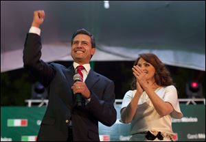 Enrique Pena Nieto, presidential candidate for the Revolutionary Institutional Party, left, speaks to supporters accompanied by his wife Angelica Rivera at the party's headquarters in Mexico City, early Monday.