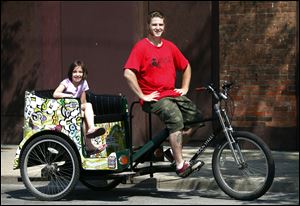 Maxwell Austin, owner of Glass City Pedicabs, and his daughter Alora, 8, show off one of the bicycle taxis that are ferrying passengers in Toledo for tips. He says he hopes to increase his fleet from four to 15 over the next five years. Riders take the pedicabs from their workplaces to lunch, from the ballpark to restaurants, or from bar to bar on weekends.