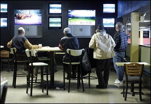 Several people watch races in one of the off-track betting areas at  Raceway Park.