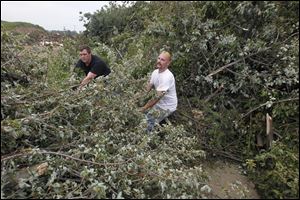 Wyatt, left, and Ben Montgomery pull tree limbs from their truck, adding to a growing pile in Findlay.