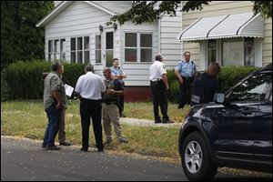 United States Marshals and members of the Toledo Police Department stand in front of a house where a man was shot.