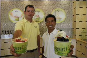 Yogurt Vi corporate operations assistant Mike Musilli, left, and manager Ek Navamal, both of Perrysburg, show off the desserts they created in the self-serve store.
