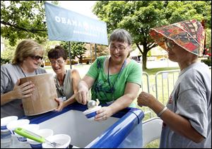 Volunteers Jane Morgan, left, and Diane Ostheimer lift an ice cream container as Kerin Hall, center, fills a dish for Elie Alda in Sandusky as they wait for the President.