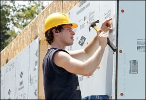Volunteer Jake Bourey braves the heat to work on the three-bedroom Habitat house that will be occupied by a woman and her two young children. The house is expected to be finished by the end of July. 