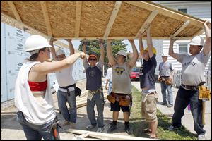 Volunteer Kerri Gangwer, left, leads volunteers from Sylvania United Church of Christ and The Temple-Congregation Shomer Emunim in raising part a Habitat for Humanity house on Gramercy Avenue, between Detroit and Lewis avenues in West Toledo.