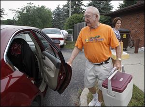 LeRoy Bunge loads his car with lunches as his granddaughter Traci Grams looks on. Mr. Bunge has been a driver for 10 years and makes three to five runs a week in Bedford Township.