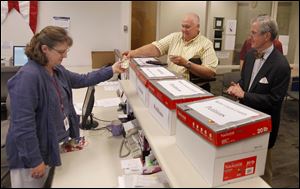 Campaign Finance Dept. worker Lori Jacek accepts petitions from Thomas Palmer, center, and Bob Reinbolt, who turned in their petitions to the Lucas County Board of Elections at the Government Center in Toledo, Ohio. The men are members of a citizens group working to place a county reform measure onto the November ballot.