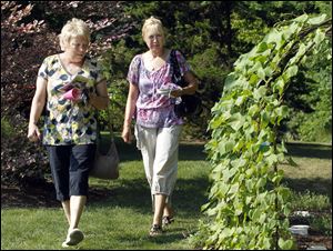 Pat Patton, left, and Debbie Zogaib, right, of Temperance, walk through the gardens at the annual Bedford Flower and Garden Club Tour.