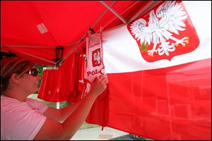 Amy Koles puts up flags and other goodies in the Polish Pride booth before the opening of a previous Lagrange Street Polish Festival.