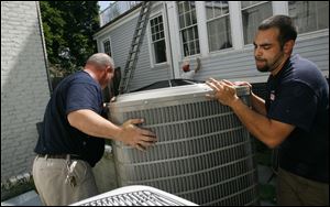 Contractors install an air conditioner in Maryland. The recent heat wave meant more air conditioning and electricity use. But long-term factors are behind a national increase in electricity prices. 