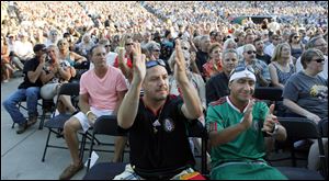 Gonzalo Estrada, left, and Gabriel Hernandez, both of Ann Arbor, applaud as Carlos Santana appears in concert at the Toledo Zoo.